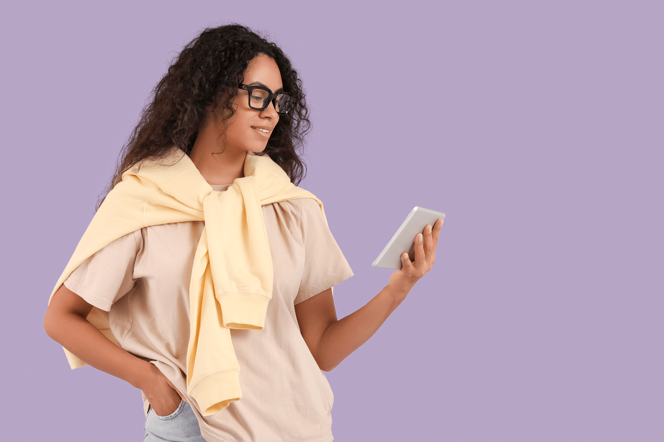 De leerkracht staat met één hand in haar zak en kijkt naar iets op haar scherm