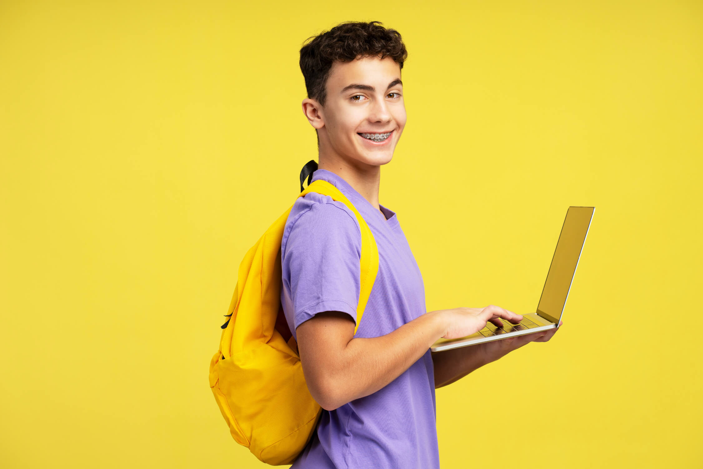 Lachende student met laptop en gele rugzak